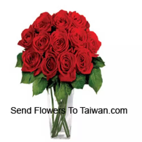 15 красных роз с папоротниками в стеклянной вазе